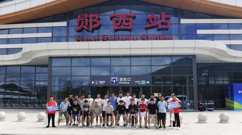 来郧参加比赛的华中科技大学足球健儿在郧西高铁站前合影留念(仵现 摄)