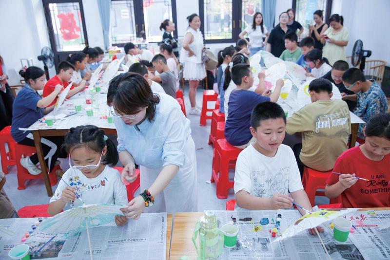 志愿者指导孩子们自己动手绘制伞面(徐慧 摄)