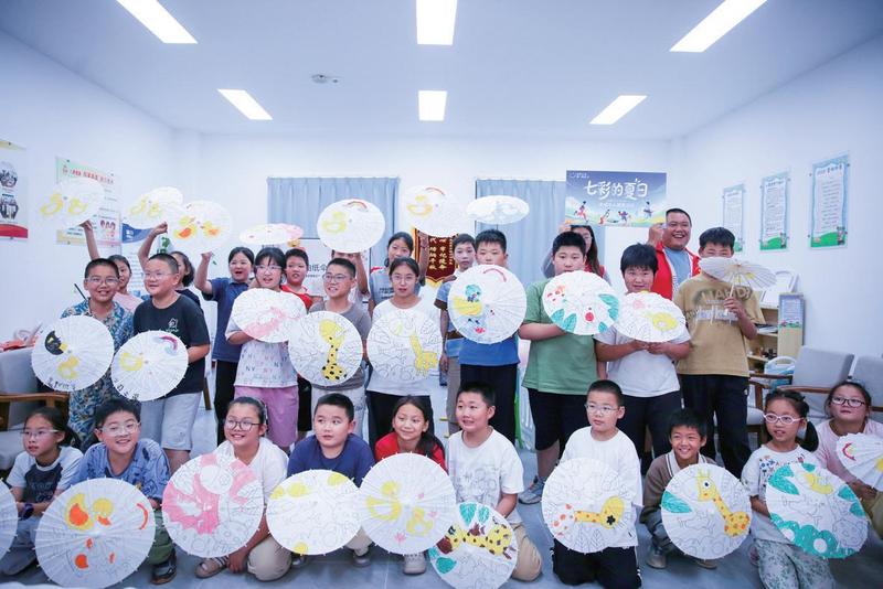 志愿者指导孩子们自己动手绘制伞面(徐慧 摄)
