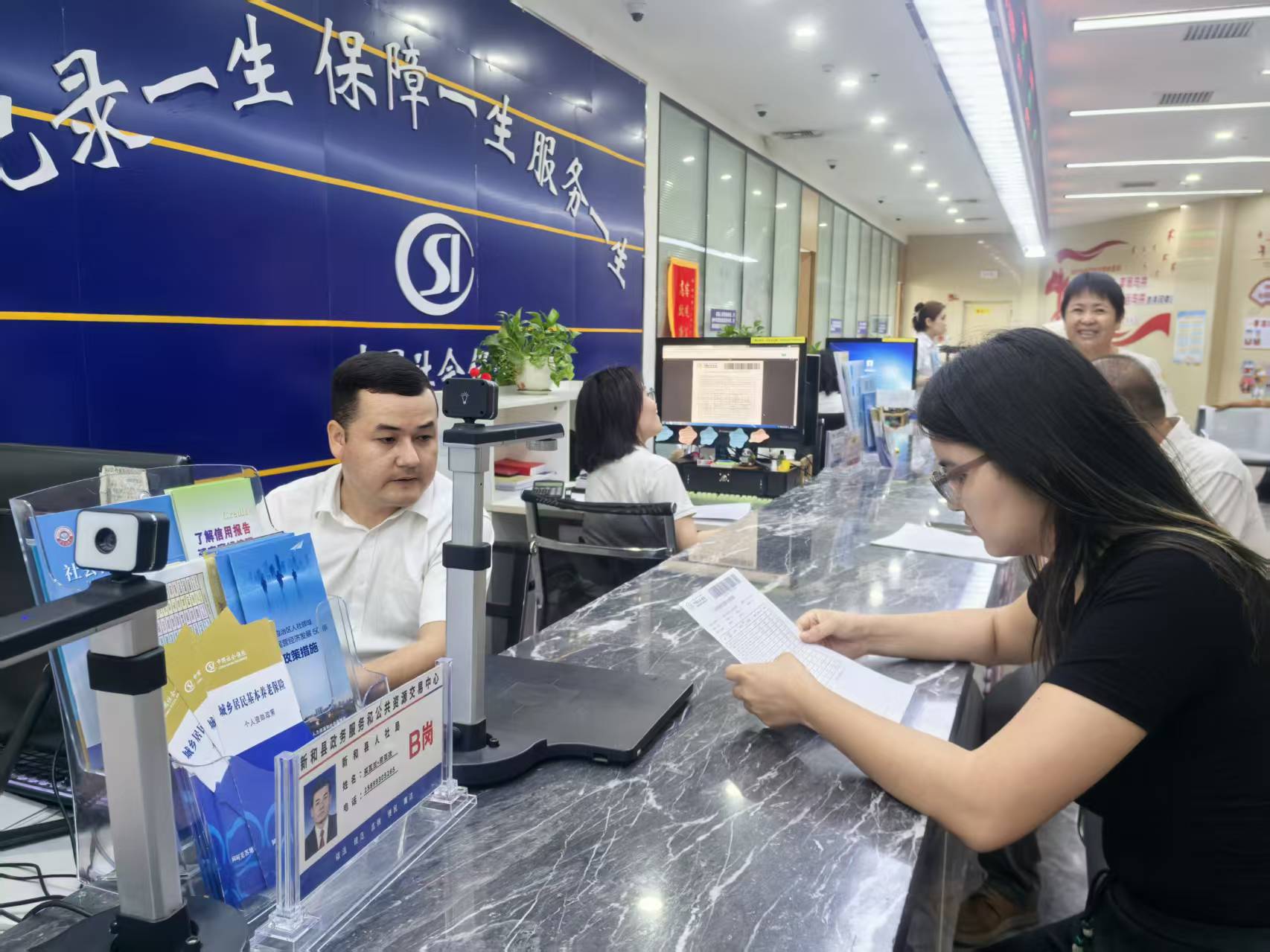 新和县人社局工作人员在服务大厅为群众办理社保相关业务(查燕荣 摄)