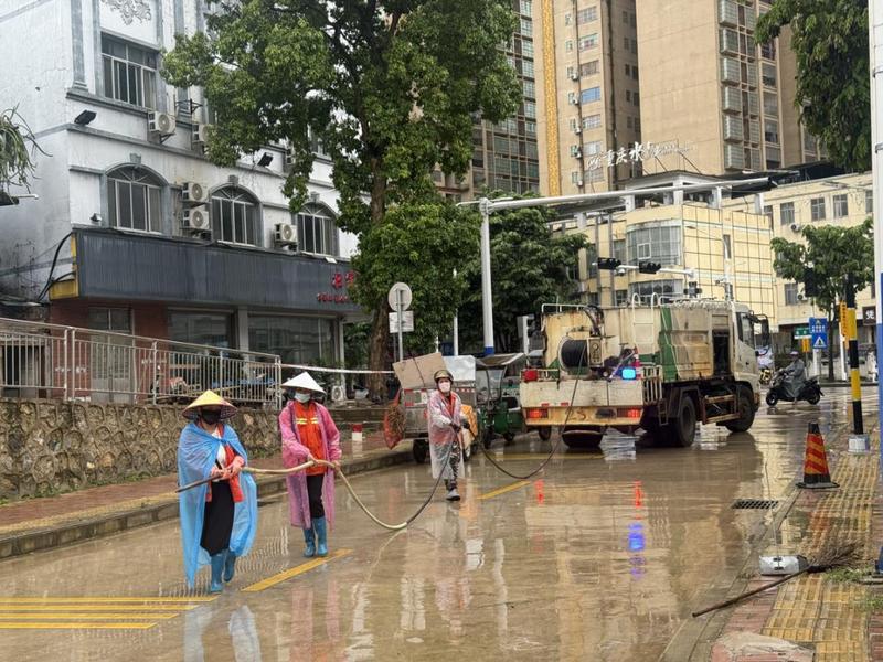 南大路铁路下穿路口,环卫工人手持扫帚清扫路面淤泥杂物。(农华艳 摄)