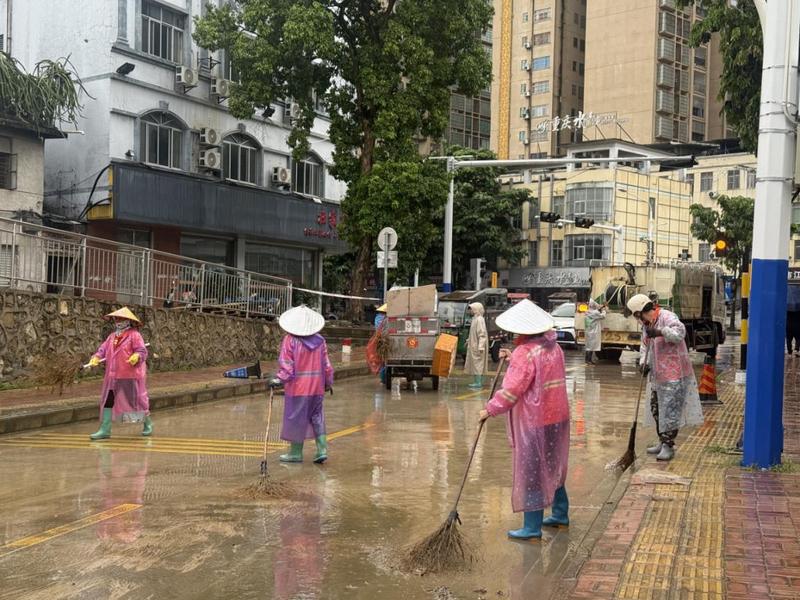 南大路铁路下穿路口,工作人员对路边绿化带、墙根处的垃圾杂物进行清扫清运。(农华艳 摄)