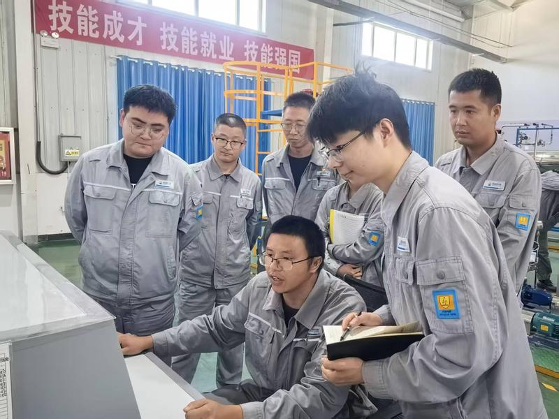 王文凯与同事依托化工仿真模拟系统练习工艺流程操作,锤炼岗位实操技能。(查燕荣 摄)