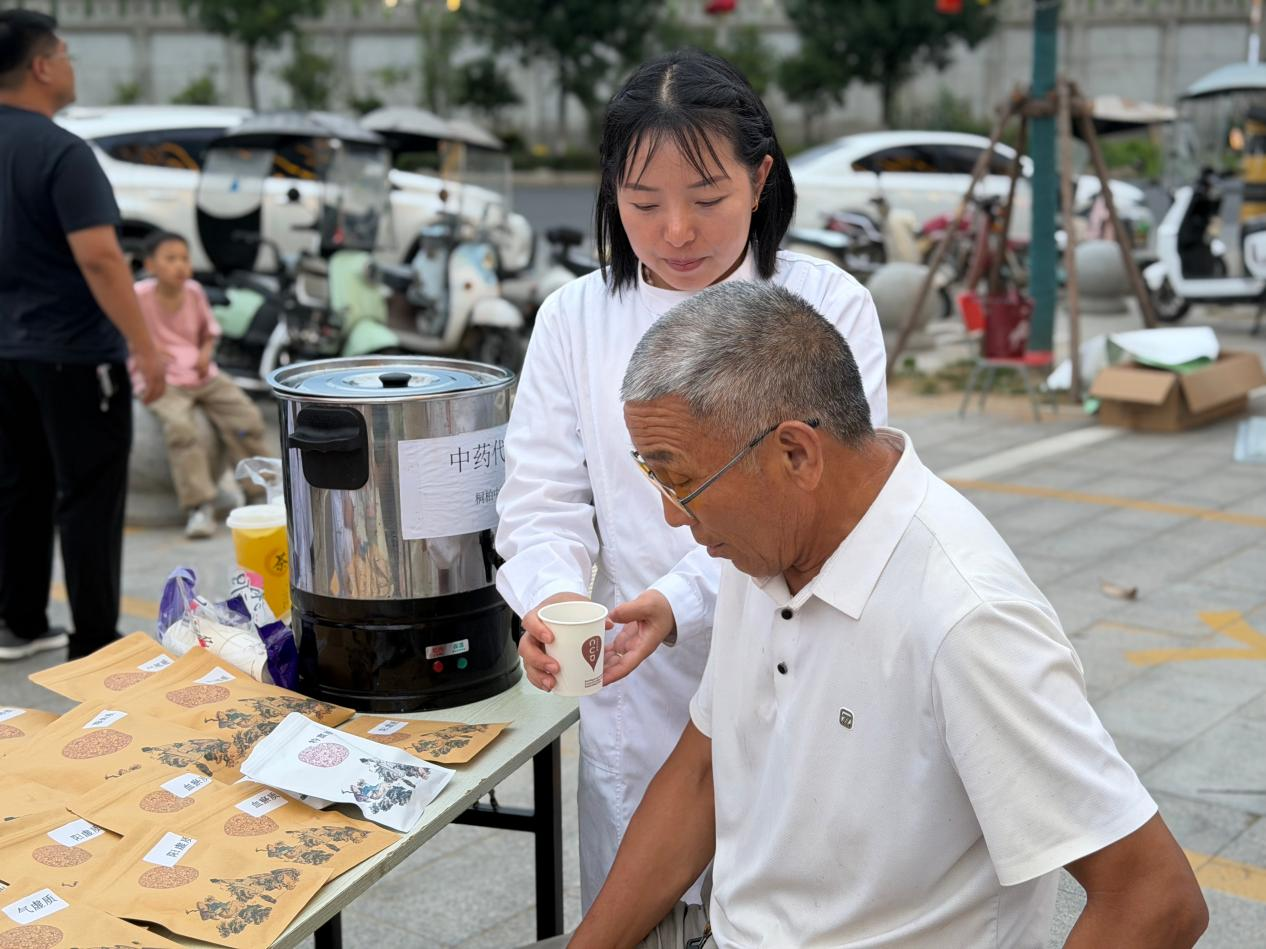 医务人员为前来接受服务的居民端送养生茶饮 (刘蕊 摄)