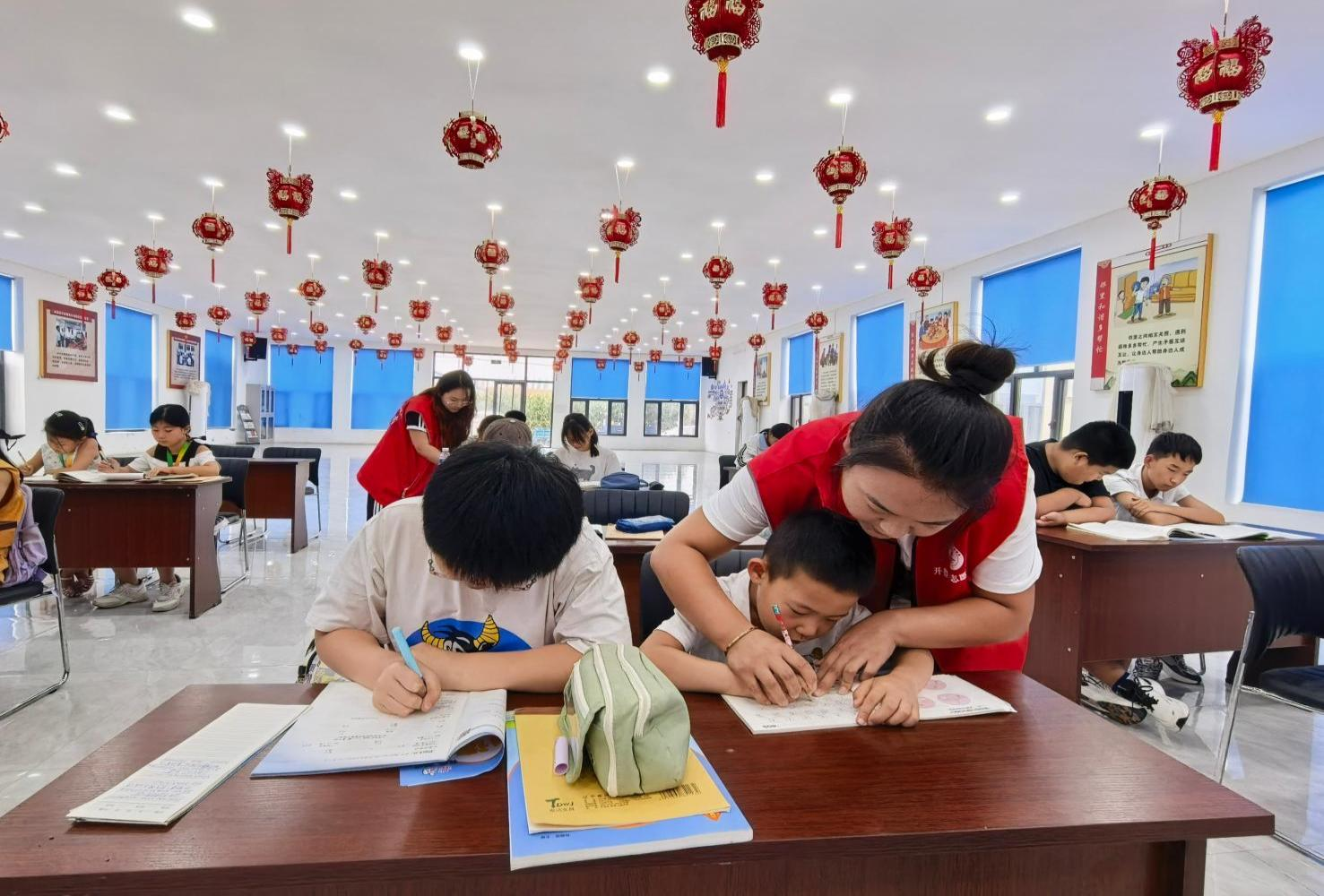 大学生志愿者王淑繁(右一)辅导小学生正确握笔(张楠 摄)