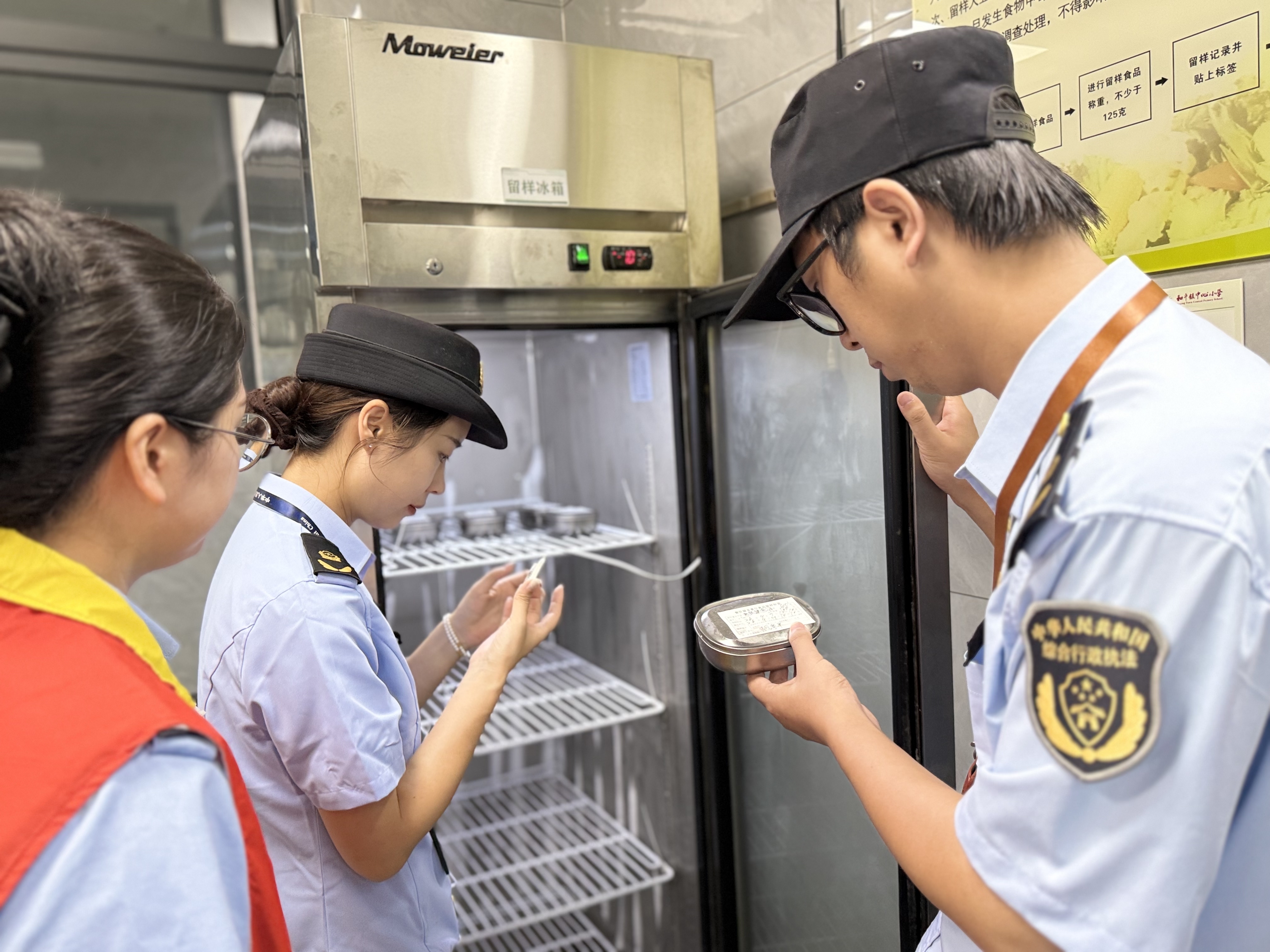 执法人员在学校食堂对食品留样和台账进行检查对比 (邹静 摄)