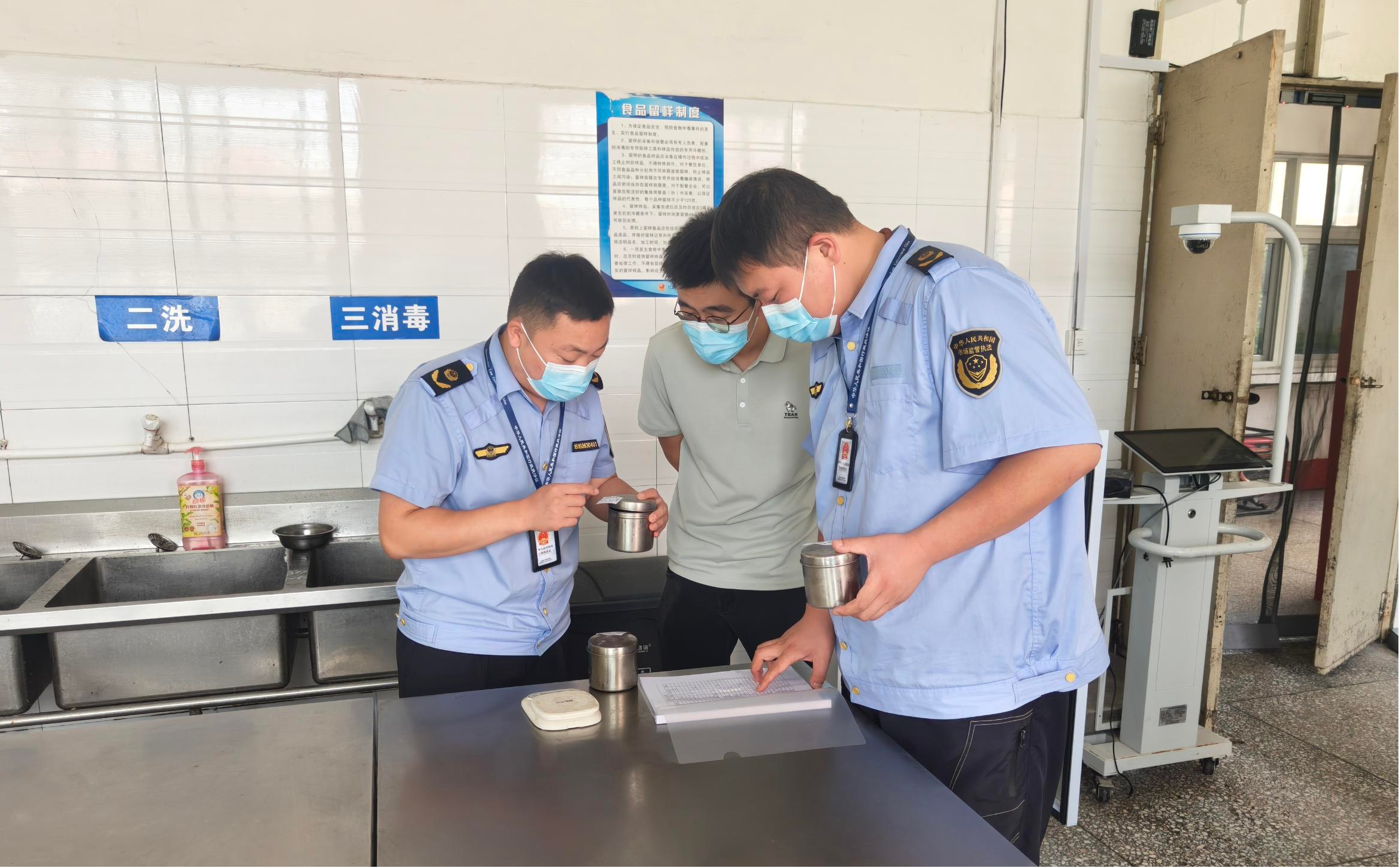 执法人员在检查学校食堂食品留样及登记情况(闫红志 摄)