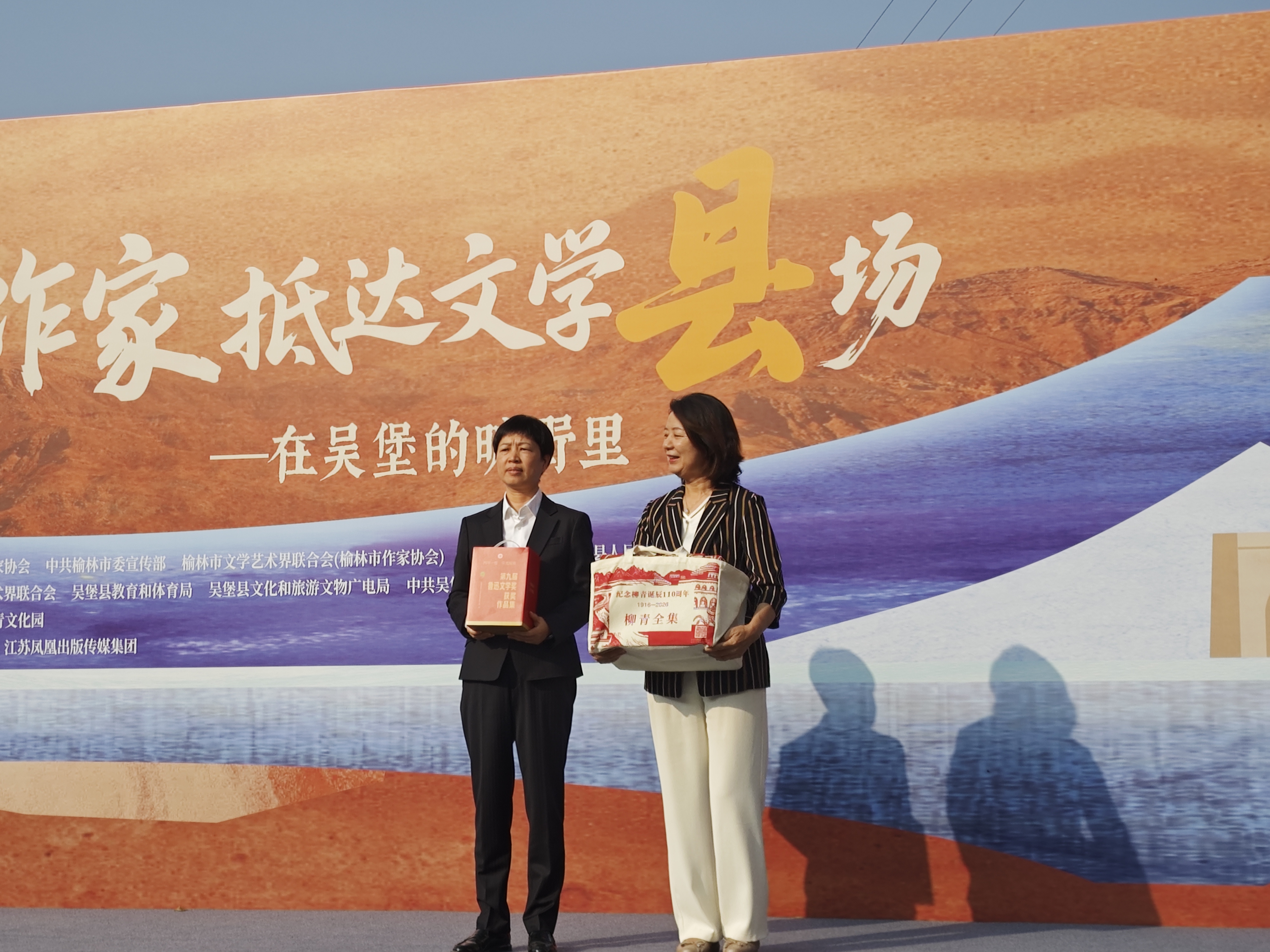 包宏烈(右)与吴堡县委副书记、县长刘荣互赠图书(梁曦 摄)