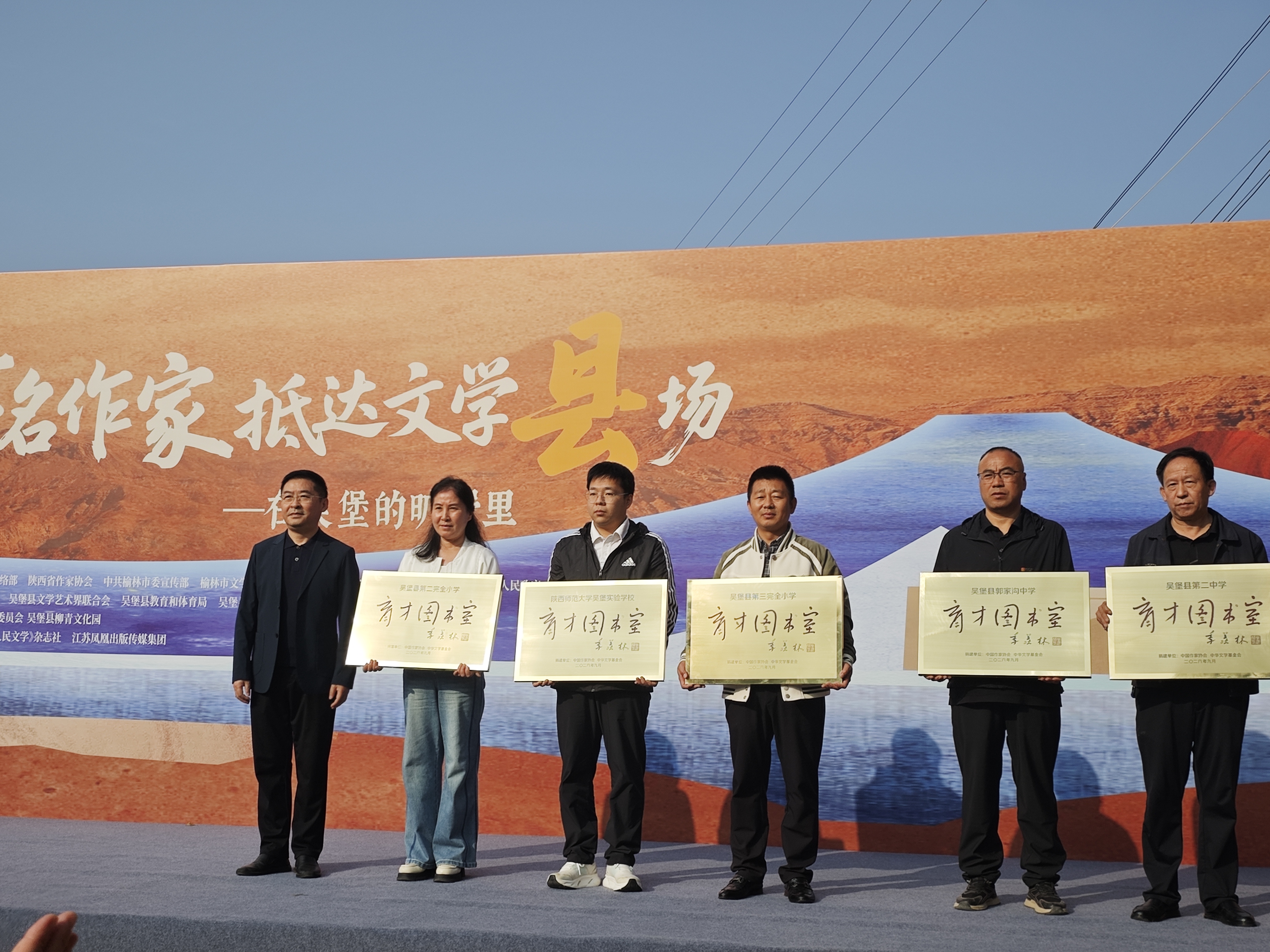 中华文学基金会副理事长兼秘书长安亚斌(左一)为“育才图书室”赠牌(梁曦 摄)
