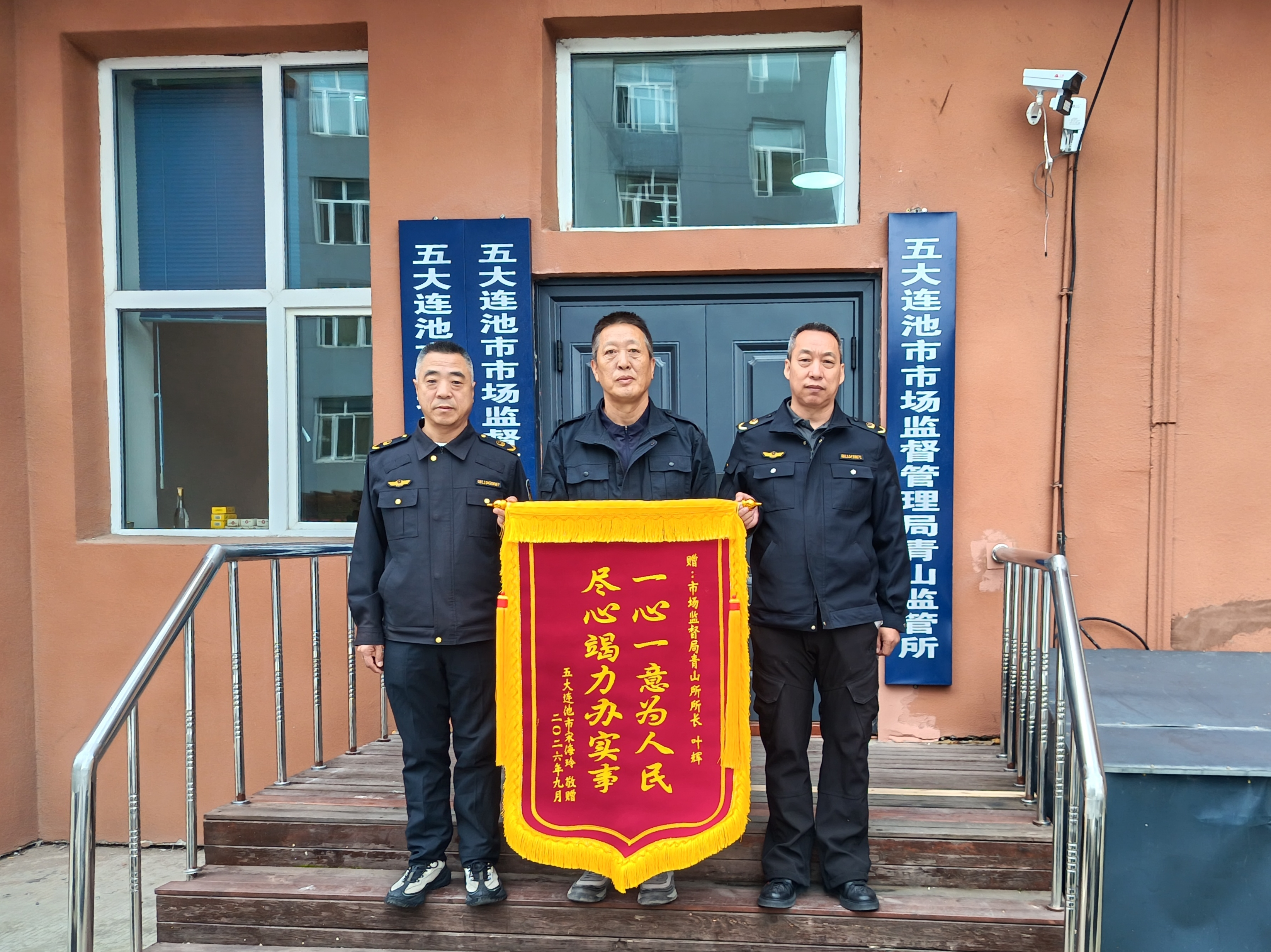 薛超家人向五大连池市市场监督管理局青山市场监管所执法人员赠送锦旗(邹凯玥 摄)