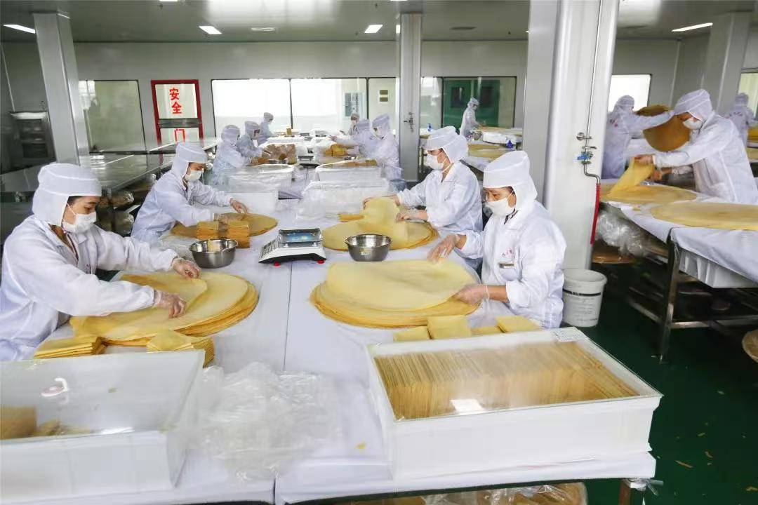 曲阜千禾食品有限公司车间里工人们穿戴整洁忙碌着叠煎饼(张雪艳 摄)