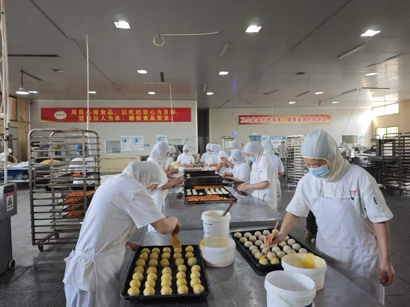 生产车间内,工作人员身穿工作服正有条不紊地制作月饼。(闫婷婷 摄)