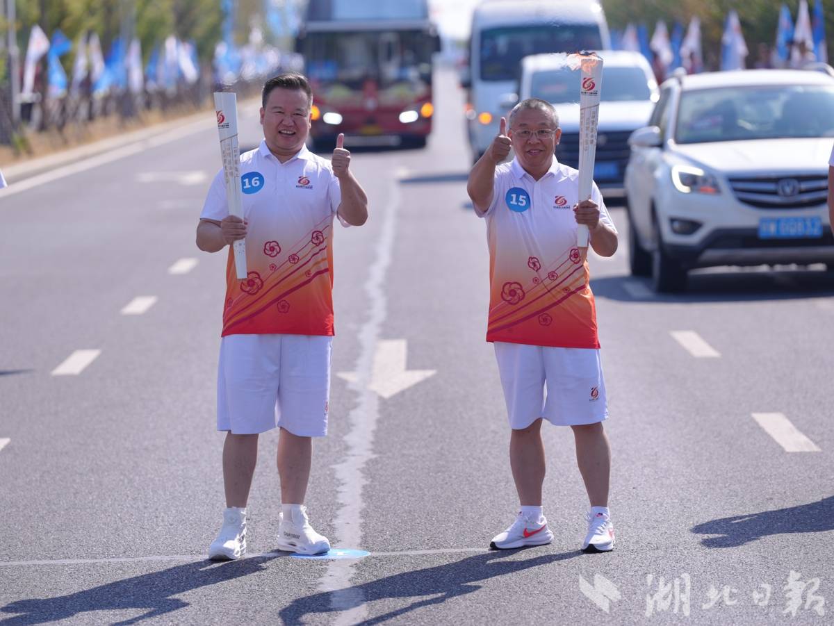 中国好人祝伟(右)与荆楚楷模刘磊(左)交接火炬。(湖北日报通讯员 徐文 摄)