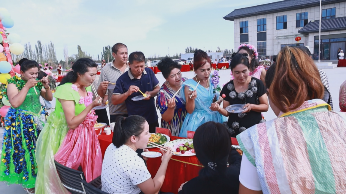 9月24日,在库车市牙哈镇团结村活动现场,各族干部群众一同品美食、唠家常。(克德尔娅·艾买提 摄)