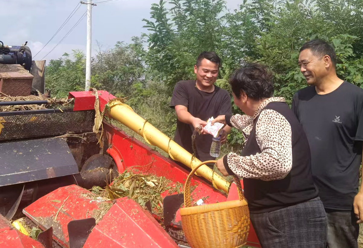 种植户李玲芝(右)为农机手(张俊财)送纯净水和食品(王世超 摄)