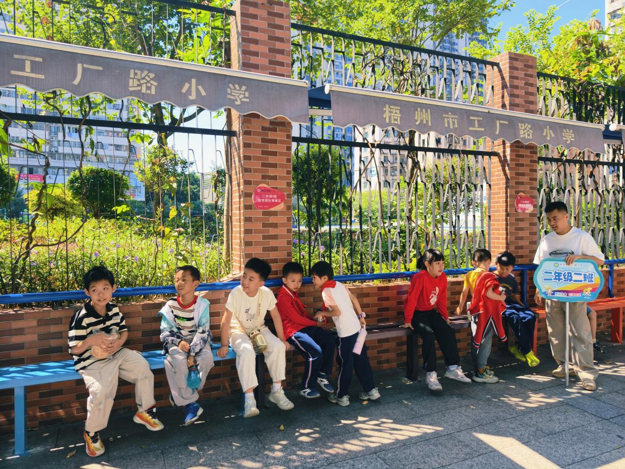 在工厂路小学门口,放学后等候家长的学生们坐在便民椅上休息(麦好明 摄)