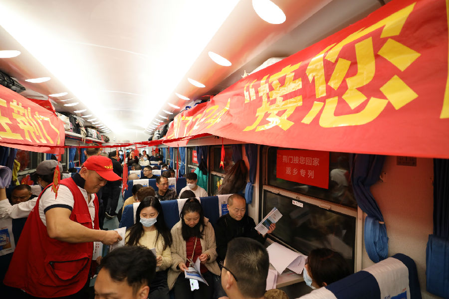 图为返乡专列上人社部门志愿者发放就业政策宣传资料 （钟国庆 摄）