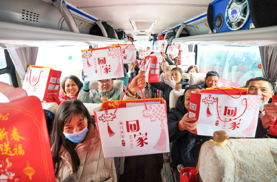 图为坐在大巴上的返乡人员收到人社部门赠送小吃和春联等手袋礼品 （钟国庆 摄）