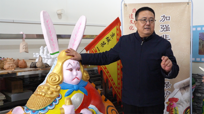 玉田县文化馆馆长胡金锋介绍巨型兔儿爷泥塑（姜妍如 摄）