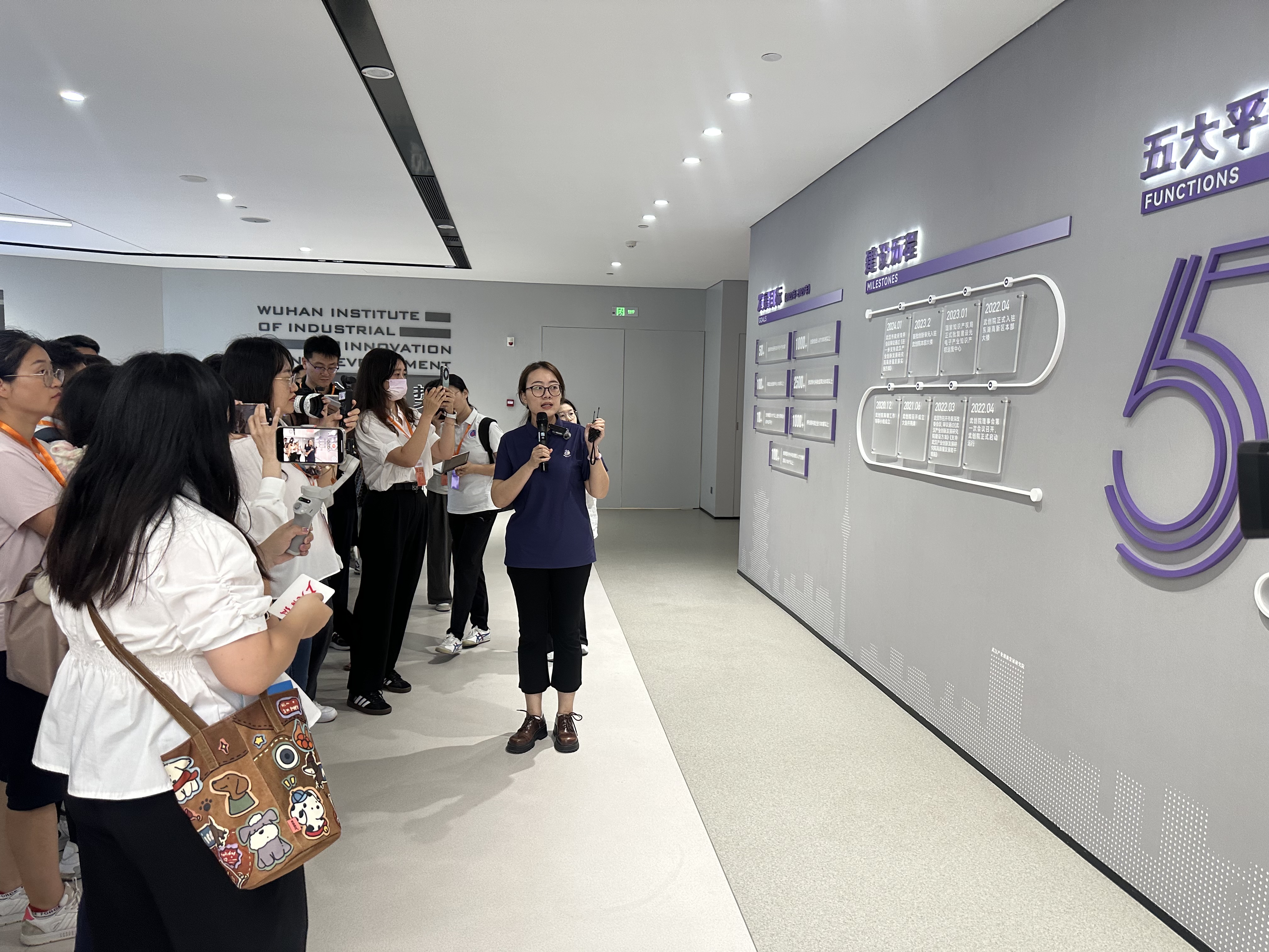 武创院行政事务部工作人员宋宵彤向记者们介绍武创院的建设历程（丛伯地 摄）