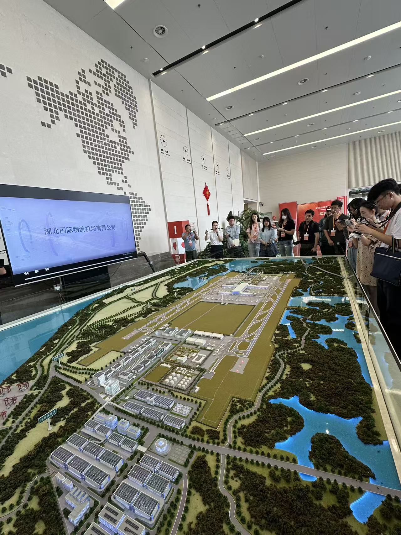 鄂州花湖国际机场工作人员向采访团的记者讲解机场沙盘模型（丛伯地 摄）