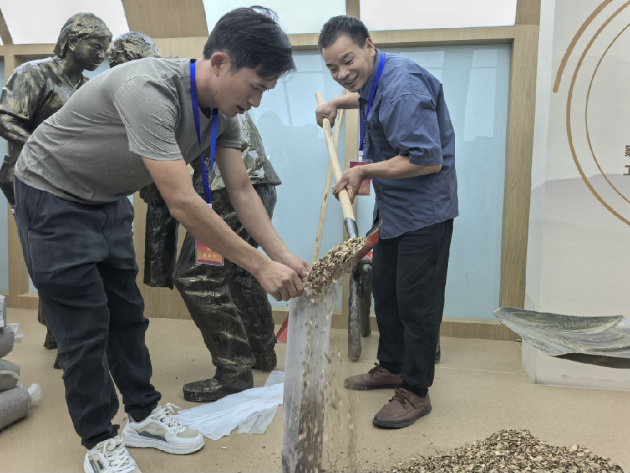  香菇种植户吴忠（右）向记者展示如何装料（余惠玲 摄）